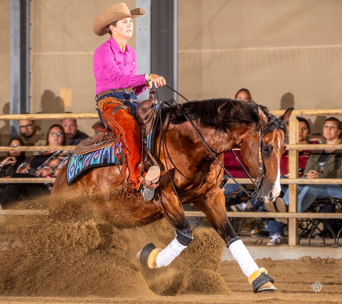 Iris Austin riding a bay reining horse through a sliding stop